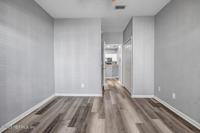 spare room featuring a ceiling fan, wood finished floors, visible vents, and baseboards