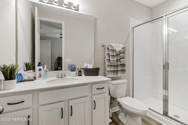 bathroom with vanity, toilet, a shower with shower door, and hardwood / wood-style floors