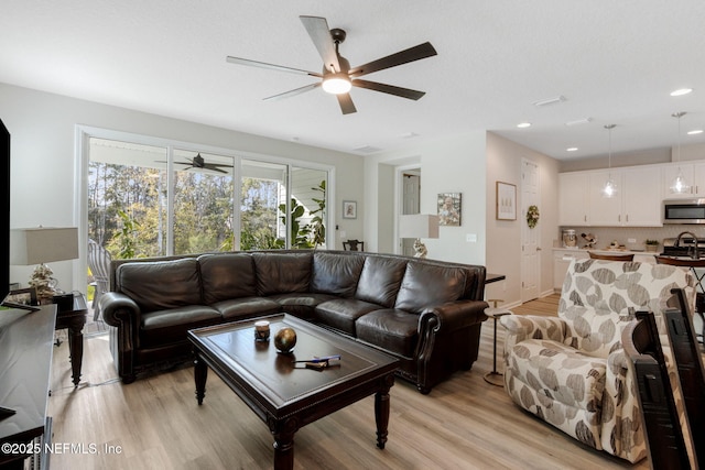 living room featuring ceiling fan and light hardwood / wood-style floors