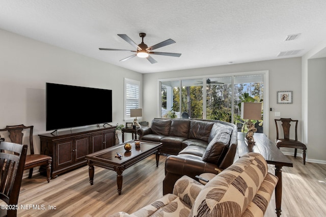 living room with a textured ceiling, light hardwood / wood-style floors, and ceiling fan