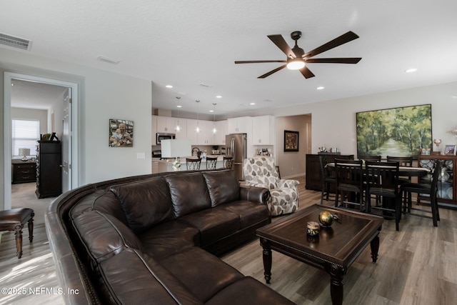 living room with light hardwood / wood-style floors and ceiling fan