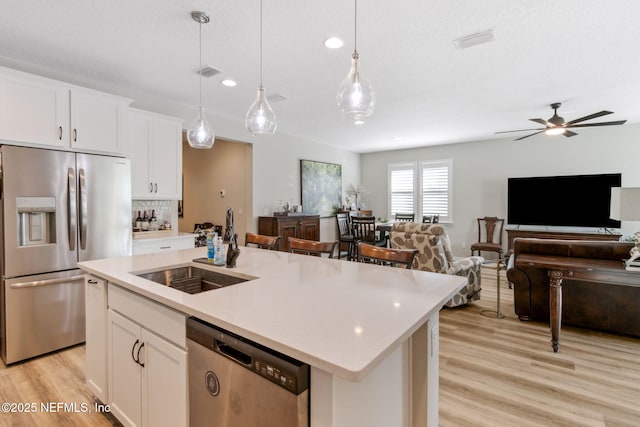 kitchen featuring sink, white cabinetry, a center island with sink, pendant lighting, and stainless steel appliances