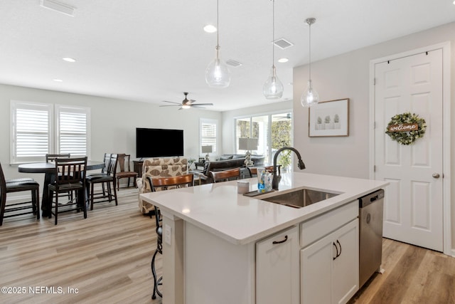 kitchen featuring a kitchen island with sink, sink, stainless steel dishwasher, and white cabinets