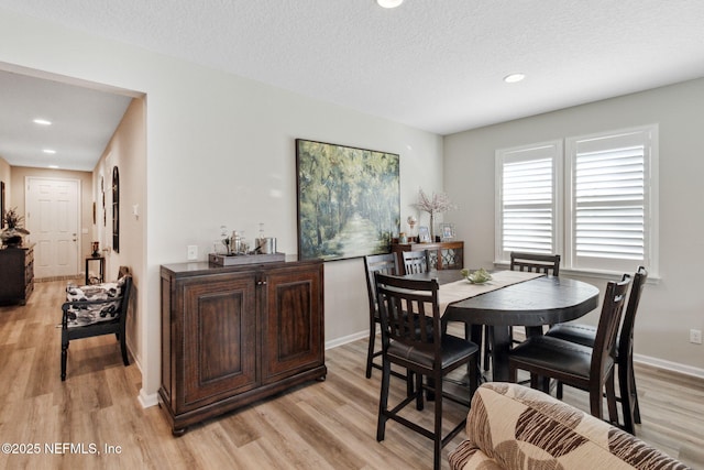 dining area featuring a textured ceiling and light wood-type flooring