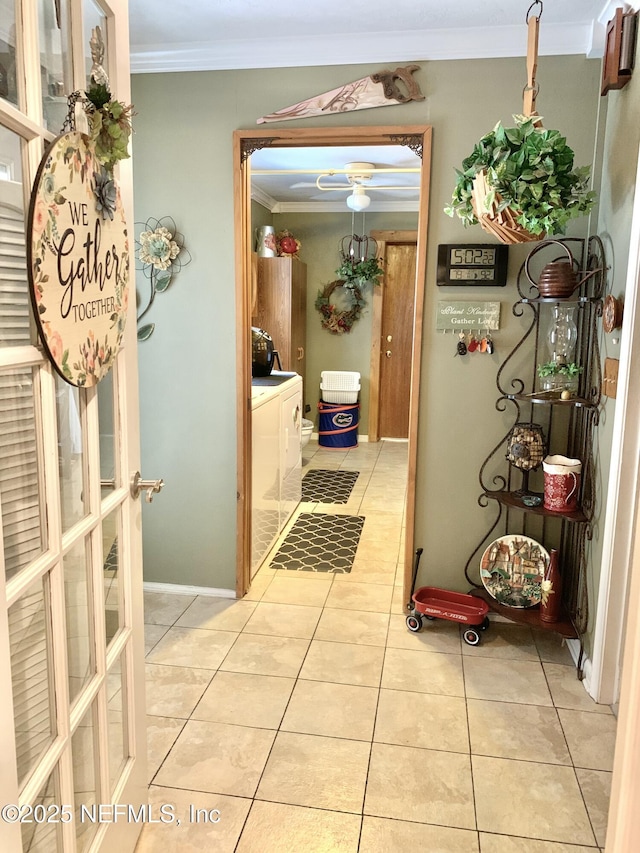 hall featuring light tile patterned floors, ornamental molding, and washing machine and clothes dryer