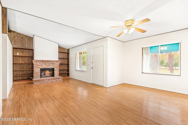 unfurnished living room with a fireplace, vaulted ceiling, a textured ceiling, and light wood-type flooring