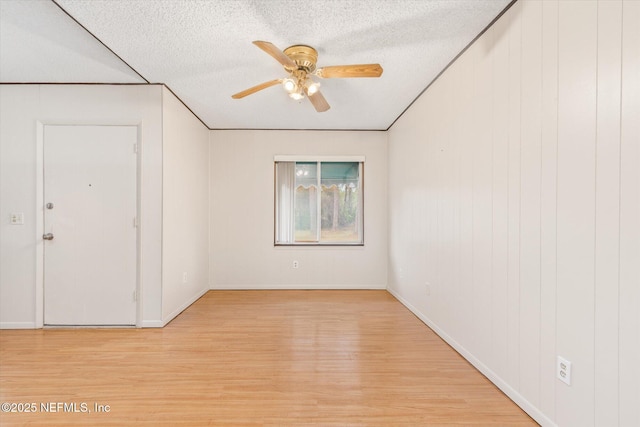 empty room featuring ceiling fan, light hardwood / wood-style floors, and a textured ceiling