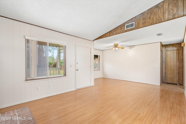 unfurnished room featuring ceiling fan, lofted ceiling, a textured ceiling, and light hardwood / wood-style flooring