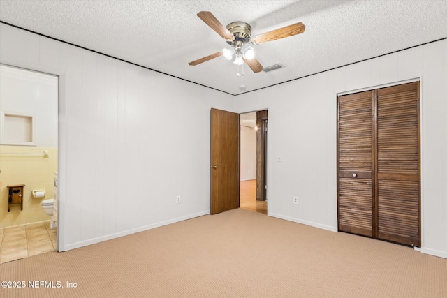 unfurnished bedroom featuring ceiling fan, light carpet, a textured ceiling, and a closet