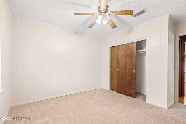 unfurnished bedroom with ceiling fan, light carpet, a closet, and a textured ceiling