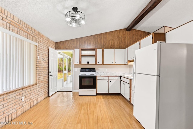 kitchen with white refrigerator, range with electric cooktop, brick wall, and white cabinetry