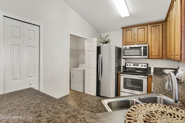 kitchen with washer / dryer, sink, lofted ceiling, stainless steel appliances, and a textured ceiling