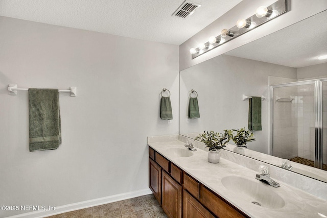 bathroom with vanity, tile patterned flooring, a shower with door, and a textured ceiling