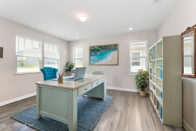 home office with light hardwood / wood-style flooring and a wealth of natural light