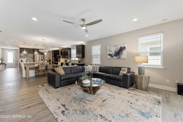 living room with ceiling fan, a textured ceiling, and light hardwood / wood-style floors