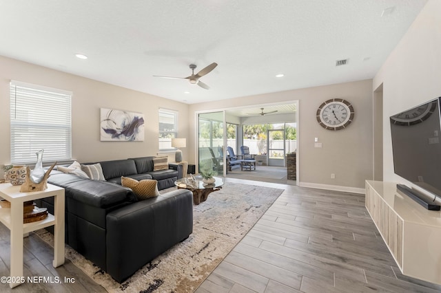 living room with a textured ceiling, wood-type flooring, and ceiling fan