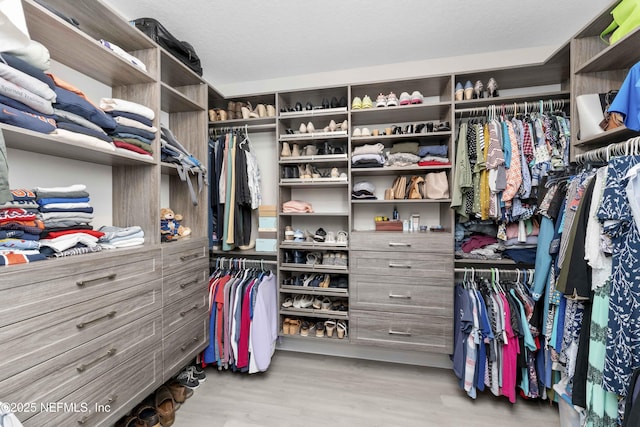 walk in closet with light hardwood / wood-style flooring