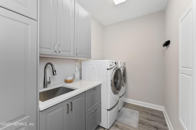 clothes washing area featuring cabinets, separate washer and dryer, sink, and light hardwood / wood-style flooring