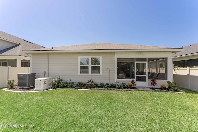 back of property with central AC, a yard, and a sunroom