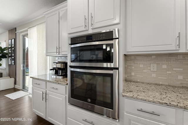 kitchen with dark hardwood / wood-style flooring, light stone countertops, white cabinets, and double oven