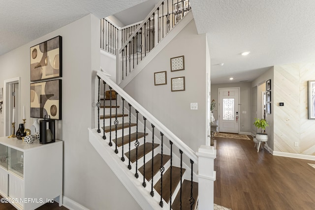 stairs featuring wood-type flooring, a textured ceiling, and wood walls