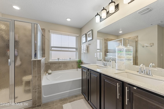 bathroom with vanity, tile patterned floors, plus walk in shower, and a textured ceiling