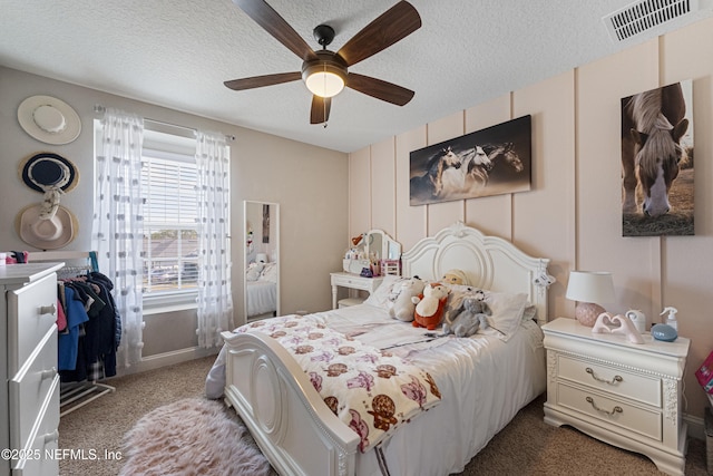 bedroom with ceiling fan, carpet, and a textured ceiling