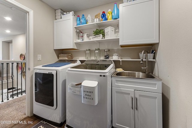 clothes washing area featuring cabinets, washing machine and clothes dryer, dark wood-type flooring, and sink