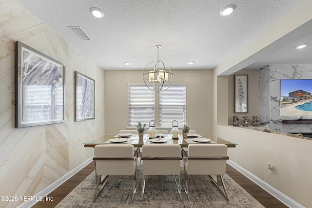 dining room featuring an inviting chandelier, wood-type flooring, and a textured ceiling