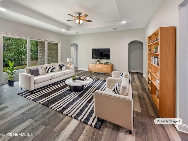 living room with a tray ceiling, ceiling fan, and hardwood / wood-style flooring