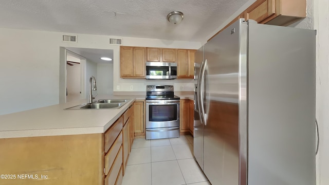 kitchen with light tile patterned flooring, sink, kitchen peninsula, stainless steel appliances, and a textured ceiling