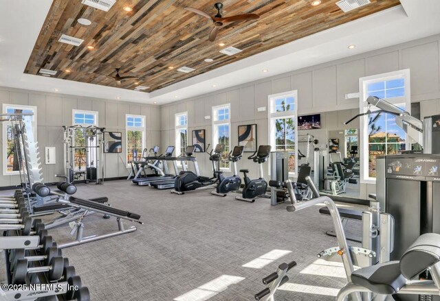 workout area featuring a decorative wall, wooden ceiling, a raised ceiling, and ceiling fan