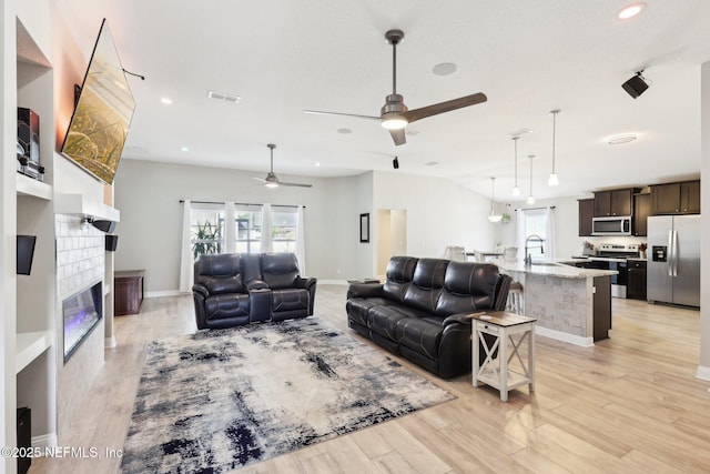 living room featuring lofted ceiling, a tile fireplace, and light hardwood / wood-style flooring