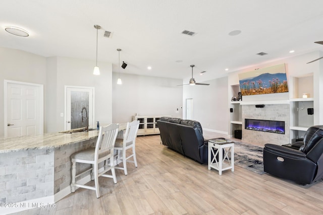 living room with sink, ceiling fan, and light wood-type flooring