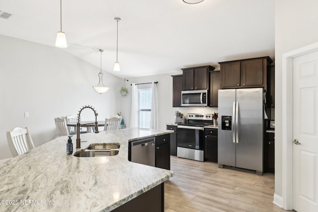 kitchen with dark brown cabinetry, sink, light stone counters, hanging light fixtures, and appliances with stainless steel finishes