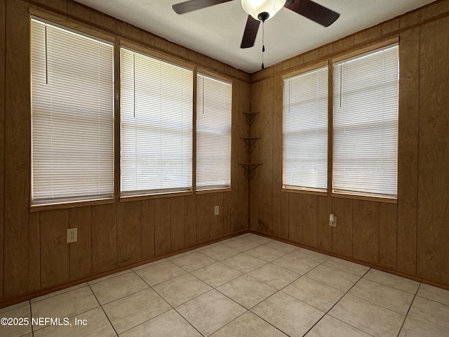 spare room with ceiling fan and wood walls