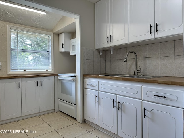 kitchen with sink, white appliances, backsplash, white cabinets, and light tile patterned flooring