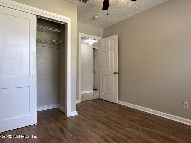 unfurnished bedroom featuring ceiling fan, dark wood-type flooring, a textured ceiling, and a closet