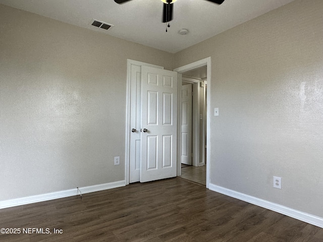 unfurnished bedroom featuring dark wood-type flooring, ceiling fan, and a closet