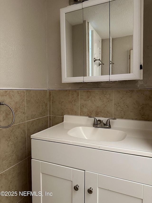 bathroom featuring vanity, tile walls, and a textured ceiling