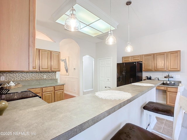 kitchen featuring a breakfast bar, light brown cabinetry, black fridge with ice dispenser, pendant lighting, and backsplash