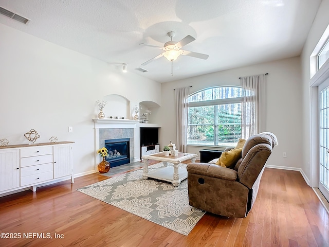 living room with hardwood / wood-style flooring, ceiling fan, a textured ceiling, and a fireplace