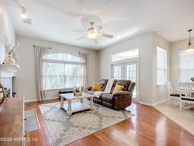 living room featuring ceiling fan, a textured ceiling, and light hardwood / wood-style floors