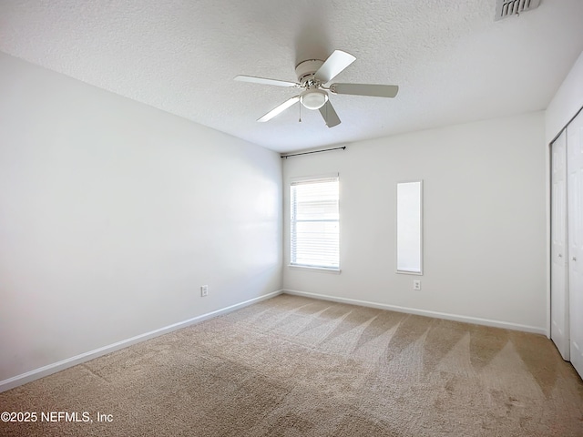 unfurnished room featuring ceiling fan, light colored carpet, and a textured ceiling