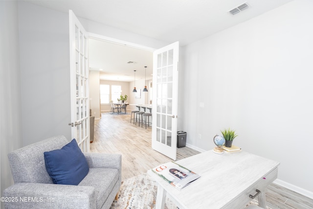 office with light hardwood / wood-style flooring and french doors