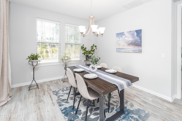 dining space with a notable chandelier and light hardwood / wood-style flooring