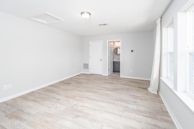 unfurnished bedroom featuring ensuite bath and light wood-type flooring