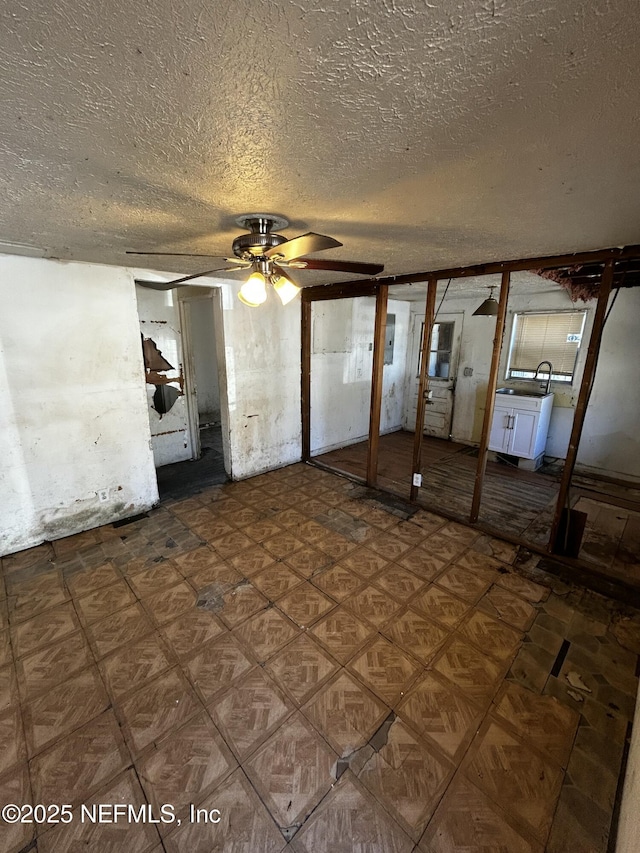 basement featuring ceiling fan and a textured ceiling