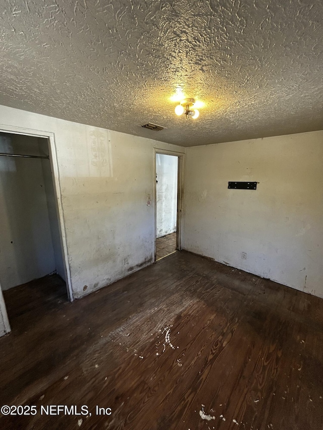 empty room with dark hardwood / wood-style flooring and a textured ceiling