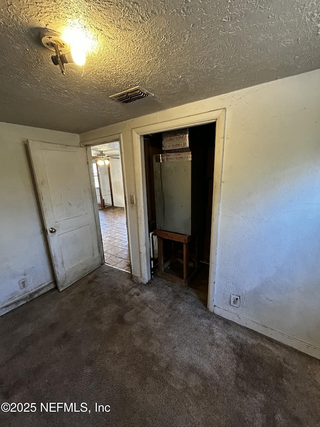 unfurnished bedroom with a closet, a textured ceiling, and dark colored carpet